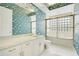 Bright bathroom with patterned wallpaper, marble countertops, and a glass-enclosed shower at 2504 Gatlin Ave, Orlando, FL 32806