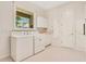 Well-organized laundry room includes machines, storage cabinets, sink, and decorated wallpaper at 2504 Gatlin Ave, Orlando, FL 32806