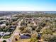 A serene aerial scene features a neighborhood with tree-lined streets and homes near a lake at 32804 Blossom Ln, Leesburg, FL 34788