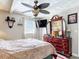 Serene bedroom featuring a large dresser, ceiling fan, and a comfortable bed with a patterned comforter at 32804 Blossom Ln, Leesburg, FL 34788