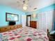 A cozy bedroom with a pastel-colored quilt bed, a ceiling fan, and a wooden dresser at 32804 Blossom Ln, Leesburg, FL 34788