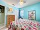Cozy bedroom with a bright blue wall, ceiling fan, and a comfortable quilt-covered bed at 32804 Blossom Ln, Leesburg, FL 34788