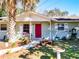 Inviting front entrance featuring a vibrant red door, well-kept garden and sitting bench at 32804 Blossom Ln, Leesburg, FL 34788