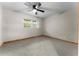 Bedroom features a ceiling fan, window and light grey carpet with natural wood trim at 38934 Sulen Rd, Lady Lake, FL 32159