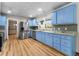 Bright kitchen featuring light blue cabinets, stainless steel appliances, granite countertops, and wood flooring at 38934 Sulen Rd, Lady Lake, FL 32159