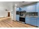 Bright kitchen featuring light blue cabinets and stainless steel appliances, with wood flooring, and an open layout at 38934 Sulen Rd, Lady Lake, FL 32159