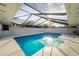 Covered outdoor pool featuring clear blue water, surrounded by a white tile deck and overhead cover at 38934 Sulen Rd, Lady Lake, FL 32159