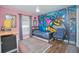 bedroom with gray wood floors, Batman graffiti on the wall, and a blue-covered bed at 5430 Pine Lilly Dr, St Cloud, FL 34771
