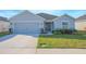 Single-story home featuring a well-manicured lawn, gray exterior paint, and attached garage at 5430 Pine Lilly Dr, St Cloud, FL 34771