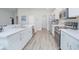 Modern kitchen with stainless steel appliances, white cabinets, large island and gray wood-look floors at 5430 Pine Lilly Dr, St Cloud, FL 34771