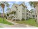 View of the condo, showing siding, walkway, green spaces, and palm trees with a blue sky overhead at 6166 Westgate Dr # 302, Orlando, FL 32835