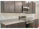 Stainless steel microwave and stove with granite countertops and gray kitchen cabinets at 6598 Lullaby Way, Mascotte, FL 34753