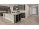 This expansive kitchen features stainless appliances, a granite island, and dark cabinets at 6598 Lullaby Way, Mascotte, FL 34753