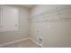 Bright laundry room featuring tile floors, utility connections, and a wire storage shelf for convenience at 6598 Lullaby Way, Mascotte, FL 34753