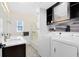 Bathroom featuring dual sinks, shower with glass doors and a laundry area with modern washer and dryer at 720 N Pennsylvania Ave, Winter Park, FL 32789
