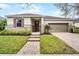 Charming home featuring a stone facade, tan siding, and a well-manicured lawn with a brick walkway and driveway at 8807 Tatara St, Orlando, FL 32836