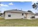 Back of house with seating area, natural colored siding, and a green lawn at 10 Pine Course Pass, Ocala, FL 34472