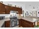 A well-equipped kitchen featuring stainless steel appliances, wooden cabinets, and a view of the living room at 10 Pine Course Pass, Ocala, FL 34472