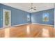 Spacious blue bedroom with hardwood floors, tray ceilings, and a ceiling fan at 1601 Billingshurst Ct, Orlando, FL 32825