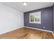 A simple bedroom with hardwood floors, a large window, and a neutral color scheme with a gray accent wall at 1913 Woodcrest Dr # B, Winter Park, FL 32792