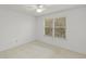 This bedroom has neutral carpet, a ceiling fan, and a large window overlooking a treed yard at 2106 Northlake Dr # 2106, Sanford, FL 32773