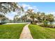 A scenic view of the tennis courts along a concrete pathway bordered by well-maintained grass and lush trees at 2106 Northlake Dr # 2106, Sanford, FL 32773