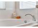 Close-up view of a soaking tub with chrome fixtures, accented by white tile and natural light at 2856 Park Meadow Dr, Apopka, FL 32703