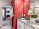 Bathroom with dual sinks, quartz counters, red wall and adjoining bedroom with bunkbeds at 2904 Penelope Loop, Kissimmee, FL 34746