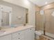 Bathroom featuring double sinks, granite countertops, and a shower with glass door at 2927 Castaway Ln, Kissimmee, FL 34747