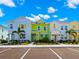 View of colorful townhomes with lush palm trees, vibrant paint, and neatly striped parking spaces at 2927 Castaway Ln, Kissimmee, FL 34747