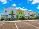 Street view showcasing colorful townhomes with parking spaces, trees, and vibrant architectural details at 2927 Castaway Ln, Kissimmee, FL 34747