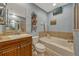 Well-lit bathroom with a vanity, soaking tub, magazine rack, and neutral tile accents at 3909 Messina Dr, Lake Mary, FL 32746