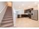 Modern, open-concept kitchen with stainless steel appliances and dark wood cabinets adjacent to carpeted stairs at 4653 Sparkling Shell Ave, Kissimmee, FL 34746