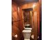 Rustic bathroom with wood paneling, toilet, sink, and small mirror at 491 Grandview Ave, Ormond Beach, FL 32176