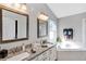 Bright bathroom featuring double sinks with granite countertops, soaking tub, and natural light at 515 Mickleton Loop, Ocoee, FL 34761