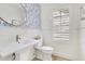 Stylish powder room with blue accent wallpaper, a large mirror, and white wainscoting at 5238 Baskin St, Orlando, FL 32814