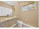 Well-lit bathroom featuring granite countertop, sink, toilet, and window at 7661 Recife Dr, Kissimmee, FL 34747