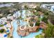 Aerial view of a resort-style pool with a lazy river, water slides, and cabanas surrounded by palm trees at 7838 Spectrum Dr, Kissimmee, FL 34747