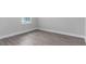 Unfurnished bedroom with gray wood floors, white trim, and a window at 7838 Spectrum Dr, Kissimmee, FL 34747