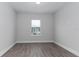 Unfurnished bedroom with gray wood floors, white trim, and a window at 7838 Spectrum Dr, Kissimmee, FL 34747