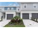 Charming townhome featuring a modern garage, a landscaped yard, and a welcoming blue door entrance at 7838 Spectrum Dr, Kissimmee, FL 34747