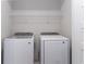 Bright laundry room with white side-by-side washer and dryer and a wire shelf at 7838 Spectrum Dr, Kissimmee, FL 34747