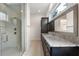 Bathroom featuring a shower with glass door and gray tile, dark cabinets, and granite countertop at 10912 Mobberley Cir, Orlando, FL 32832