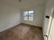 A carpeted bedroom with neutral walls features a window providing a view of the neighborhood at 1463 Riverboat Dr, Kissimmee, FL 34744