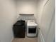 Laundry area with a modern washer and dryer set against a white wall with a shelf at 1463 Riverboat Dr, Kissimmee, FL 34744