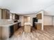 Modern kitchen featuring an island, dark cabinets, stainless steel appliances, and wood-look flooring at 1510 Oak Ln, Casselberry, FL 32707