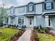 Stylish light blue townhome with dark trim, offering a landscaped front yard and inviting covered entry at 15352 Burgtheater Dr, Winter Garden, FL 34787