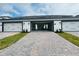 A two car garage with black and white trim, a paved driveway, and green landscaping at 15352 Burgtheater Dr, Winter Garden, FL 34787