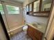 Bright bathroom featuring a shower over tub, a window, and a vanity with storage and mirrored cabinet at 1703 Doreen Ave, Ocoee, FL 34761