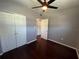 Bedroom with hardwood flooring, neutral paint, ceiling fan, and closet, creating a serene space at 1703 Doreen Ave, Ocoee, FL 34761
